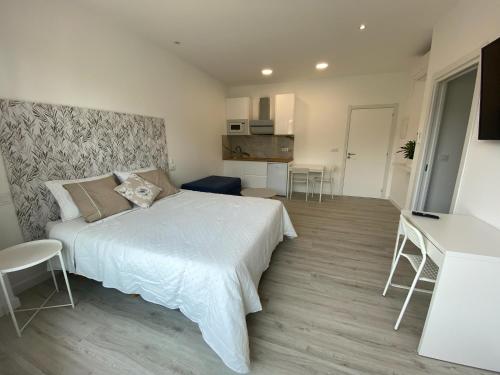 a bedroom with a large white bed and a kitchen at Camiño da Praia in Redondela