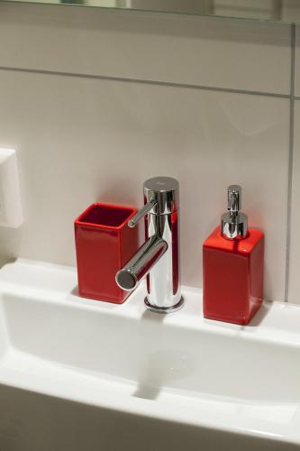a bathroom sink with a faucet and two red boxes at Kuwadro Guesthouse Jordaan in Amsterdam