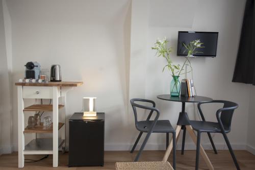 a table and chairs and a table with a vase of flowers at Kuwadro Guesthouse Jordaan in Amsterdam