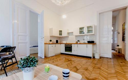 a large kitchen with white cabinets and a wooden floor at Cozy 2 Bedroom Apartment In Terez Boulevard. in Budapest