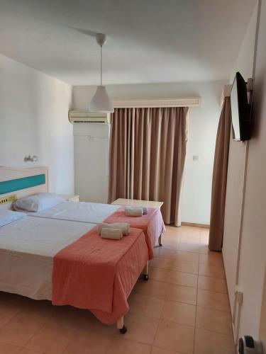 two beds in a hotel room with red sheets at Seagull Hotel Apartments in Protaras