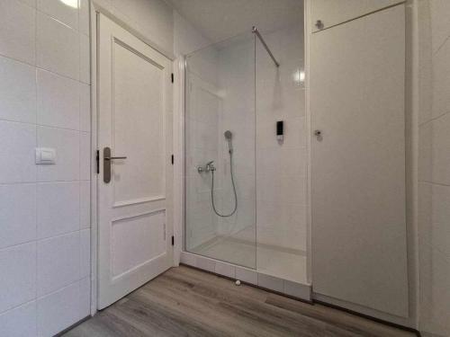 uma casa de banho com um chuveiro e uma porta de vidro em Apartamento en la Playa em Melenara
