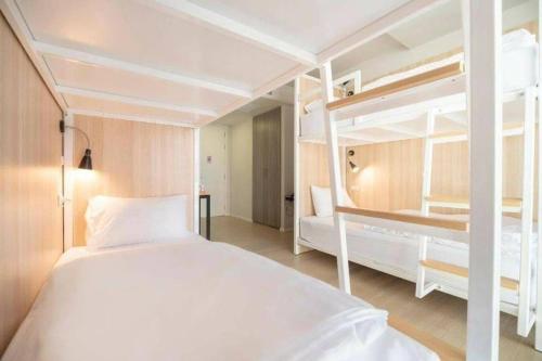a white bedroom with two bunk beds in it at Kitzio House Hotel Huai Kwang in Ban Na Song