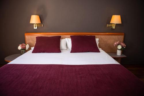 a bedroom with a large bed with purple sheets and pillows at RVHotels Spa Vila de Caldes - Adults only in Caldes de Montbui