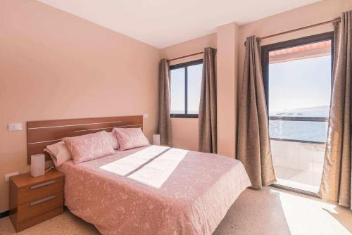a bedroom with a bed and a large window at Apartamento con preciosas vistas al mar in Melenara