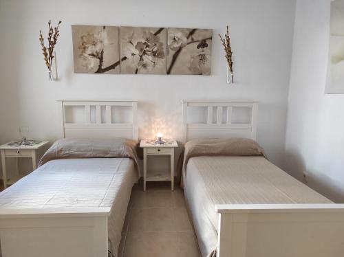 two beds in a room with two tables and a painting at Apartamento Ferrera Park 607 in Cala Ferrera