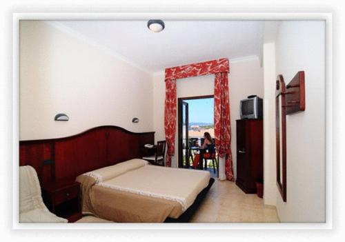 sypialnia z łóżkiem, oknem i telewizorem w obiekcie Hotel Stella Del Sud w mieście Calasetta