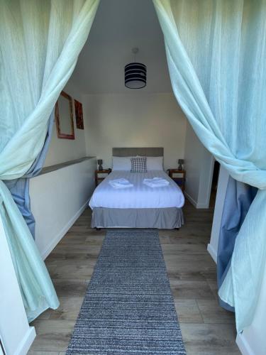 a bedroom with a bed with blue curtains and a rug at Driftwood Seagrass in Par