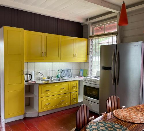 a kitchen with yellow cabinets and a stainless steel refrigerator at Max Garden and Pool in Paramaribo