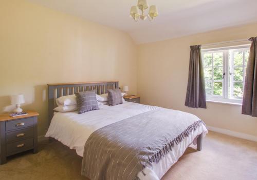 Un dormitorio con una cama grande y una ventana en Barn Meadow Cottage, en Yoxford