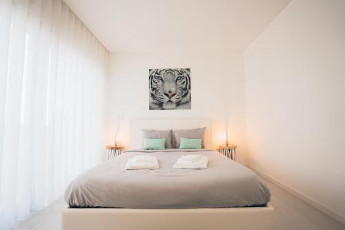 een witte slaapkamer met een bed met twee handdoeken erop bij Villa Tropical in Mariquiteira