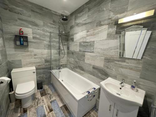 een badkamer met een toilet, een wastafel en een bad bij Driftwood Seagrass in Par
