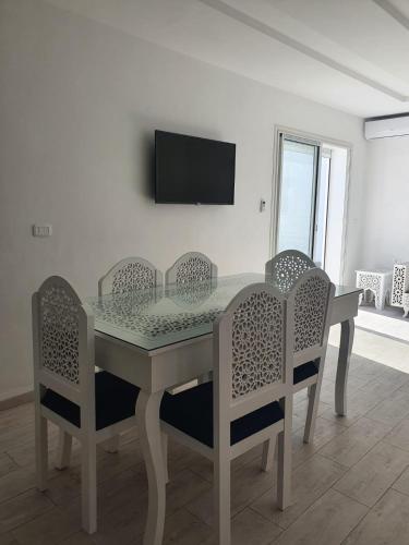a dining room table with chairs and a television on a wall at Villa de luxe avec piscine sans vis à vis Midoun in Aghīr