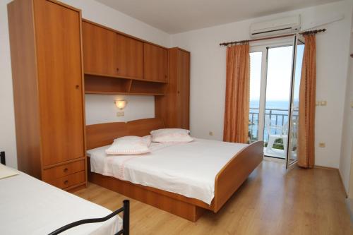 1 dormitorio con 1 cama grande y balcón en Apartments and rooms with parking space Brela, Makarska - 6895 en Brela
