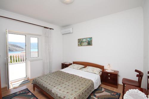 a bedroom with a bed and a large window at Apartments and rooms by the sea Metajna, Pag - 6496 in Metajna