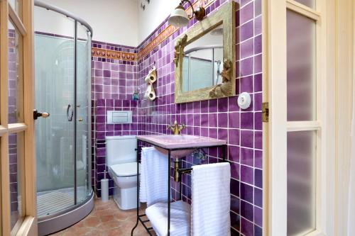 a purple tiled bathroom with a toilet and a mirror at La Mer Hotel Boutique in Cabrera de Mar