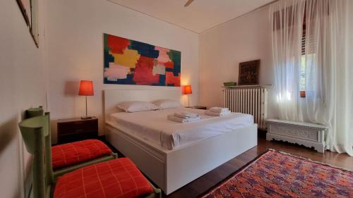 ein Schlafzimmer mit einem weißen Bett und einem Gemälde an der Wand in der Unterkunft Villa Duino Trieste Reception in Duino