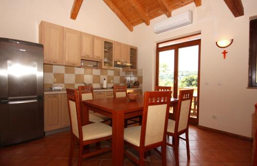 uma cozinha com uma mesa de madeira com cadeiras e um frigorífico em Seaside holiday house Tisno, Murter - 5094 em Tisno