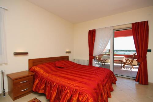 1 dormitorio con cama roja y balcón en Seaside apartments with a swimming pool Barbat, Rab - 4980 en Rab