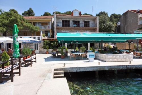 eine Terrasse mit Tischen und Sonnenschirmen neben einem Wasserkörper in der Unterkunft Rooms by the sea Pomena, Mljet - 4929 in Pomena