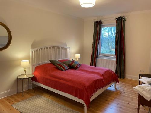 ein Schlafzimmer mit einem Bett mit einer roten Decke und einem Fenster in der Unterkunft Schellnhof Forsthaus am Waldrand in Nidda