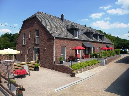a brick building with red umbrellas in front of it at Gocher Berghof Ferienwohnungen Langanke in Goch