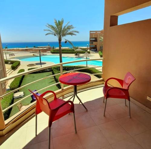 a balcony with chairs and a table and a view of a pool at Cheerful Villa - Romance Resort in Ain Sokhna