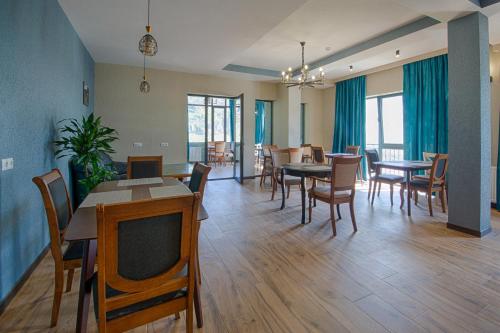 a dining room with wooden floors and tables and chairs at Hotel GENI Kazbegi in Stepantsminda