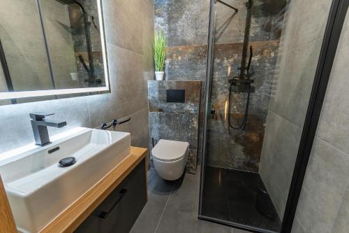 La salle de bains est pourvue d'un lavabo et d'une douche. dans l'établissement Bison Apartamenty, à Białystok