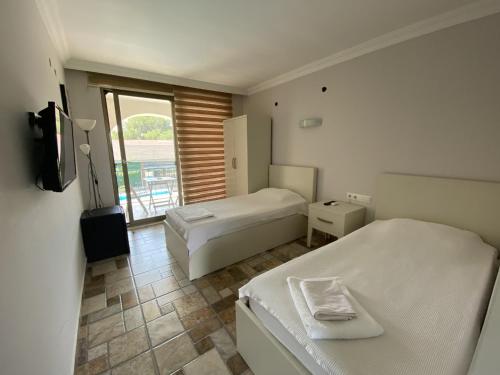 a bedroom with two beds and a tv and a window at BURÇ HOTEL in Dalaman
