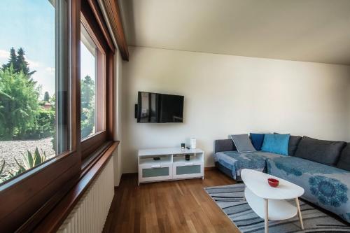 ein Wohnzimmer mit einem Sofa und einem TV in der Unterkunft Appartamento Lucino by Quokka 360 - with large terrace in Lugano