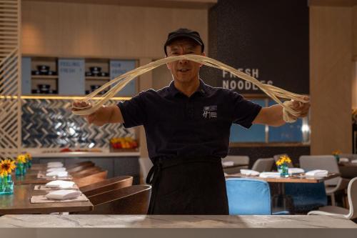 a man in a restaurant holding up a piece of food at Holiday Inn Express Lanzhou New Area by IHG in Lanzhou