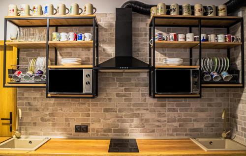 una cocina con una pared de ladrillo y estanterías en FOKA Hostel, en Wroclaw