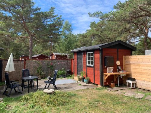 einen kleinen roten Schuppen mit einem Tisch und Stühlen in der Unterkunft Nissevikens Stugby in Havdhem