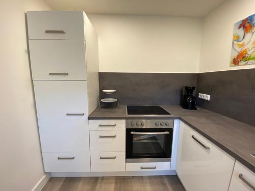 a kitchen with white cabinets and a stove at Haus am Iberg 4 in Willingen