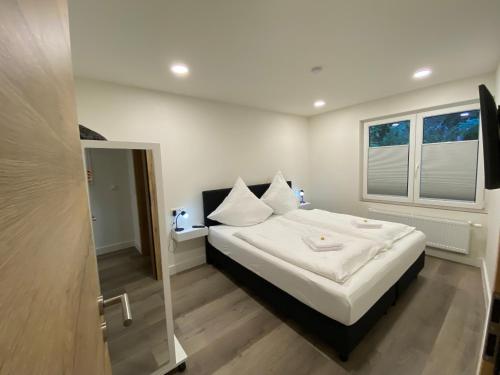 a bedroom with a bed with white sheets and a window at Haus am Iberg 4 in Willingen