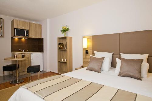 a hotel room with a large bed and a kitchen at Séjours & Affaires Strasbourg Kleber in Strasbourg