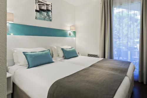 - une chambre avec un grand lit blanc et des oreillers bleus dans l'établissement Citadines Castellane Marseille, à Marseille
