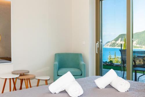 a room with a bed and a chair and a window at Mylos Mountain Villas- Villa Giorgio in Agios Nikitas