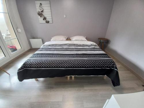a bedroom with a large bed with a black and white blanket at Une bulle de quiétude proche de Paris et Créteil in Bonneuil-sur-Marne
