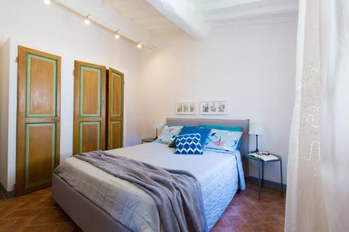 sypialnia z łóżkiem z niebieską pościelą i poduszkami w obiekcie San Domenico Central Apt w mieście San Gimignano