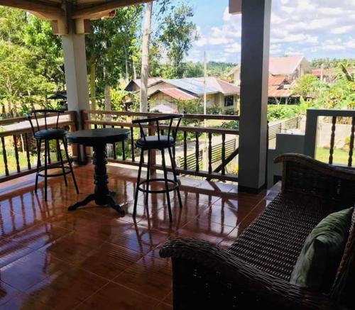 a porch with tables and stools on a balcony at MIOKI HOMETEL in Batuan