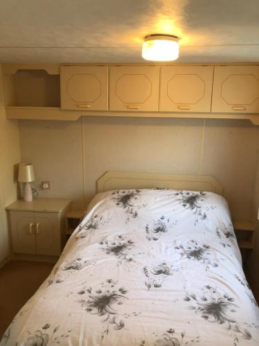 a bedroom with a bed with a white blanket with flowers at Fantasy Island and Beach 6 Berth 545 in Ingoldmells