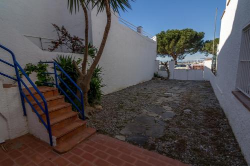 una escalera junto a un edificio blanco con una palmera en Agi Port de Rosas, en Roses
