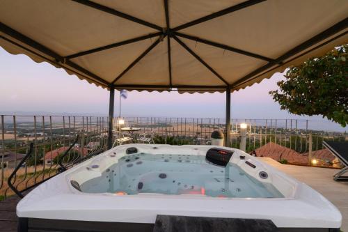 a hot tub on a patio with an umbrella at Rom Mansion in Rosh Pinna