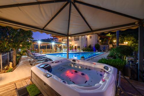 a hot tub under an umbrella next to a pool at Rom Mansion in Rosh Pinna