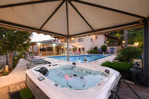 a hot tub under an umbrella next to a pool at Rom Mansion in Rosh Pinna