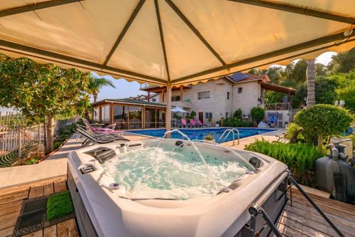 a hot tub on a deck with an umbrella at Rom Mansion in Rosh Pinna