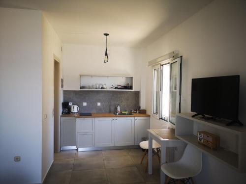a kitchen with a table and a tv in a room at 12 Gods Resort in Pylos