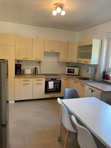 una cocina con armarios blancos y una mesa con sillas. en Ferienwohnung Diana und Manuel, en Weinheim